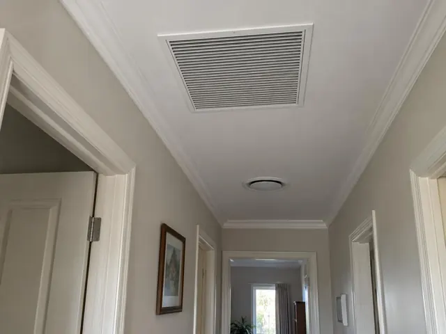 Ceiling return-air grille and wall controller in a painted hallway with door trims in Morphett Vale